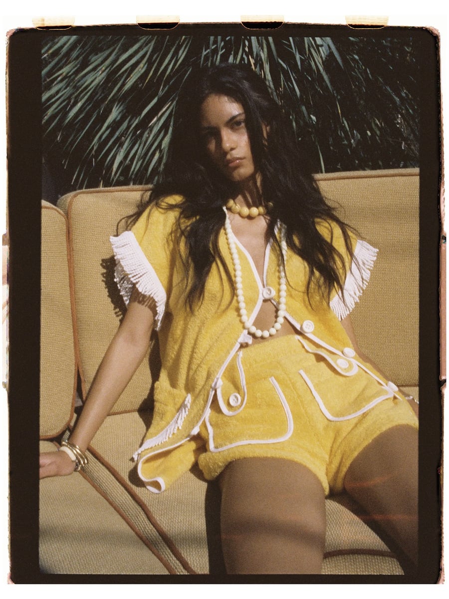 Navy blue terry cloth high-waisted shorts with white piping and front button-flap pockets, styled with a yellow and white striped lace-up bodysuit by La Veste.