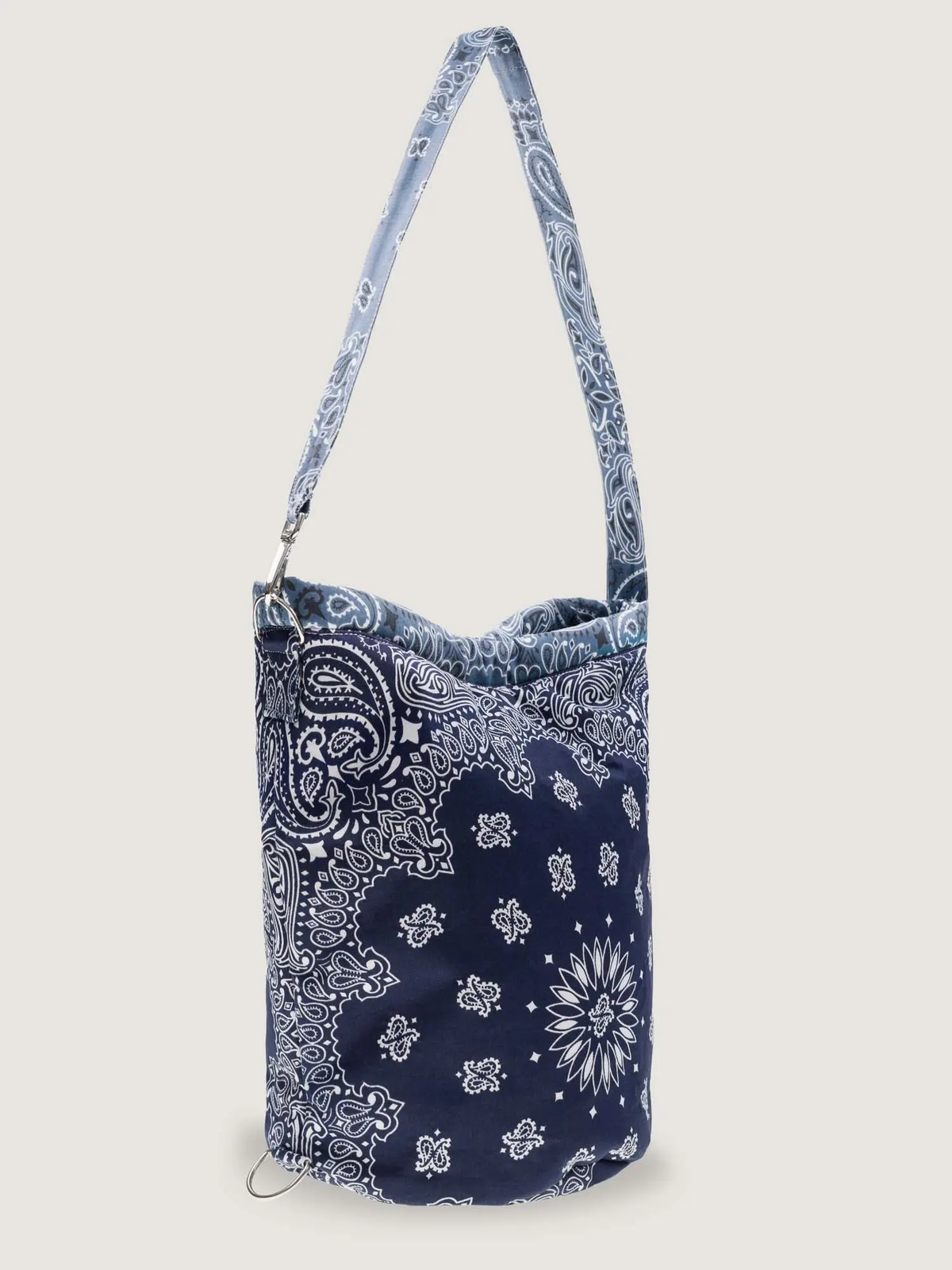 Navy bucket bag with white bandana print, long adjustable strap, and side clasp
