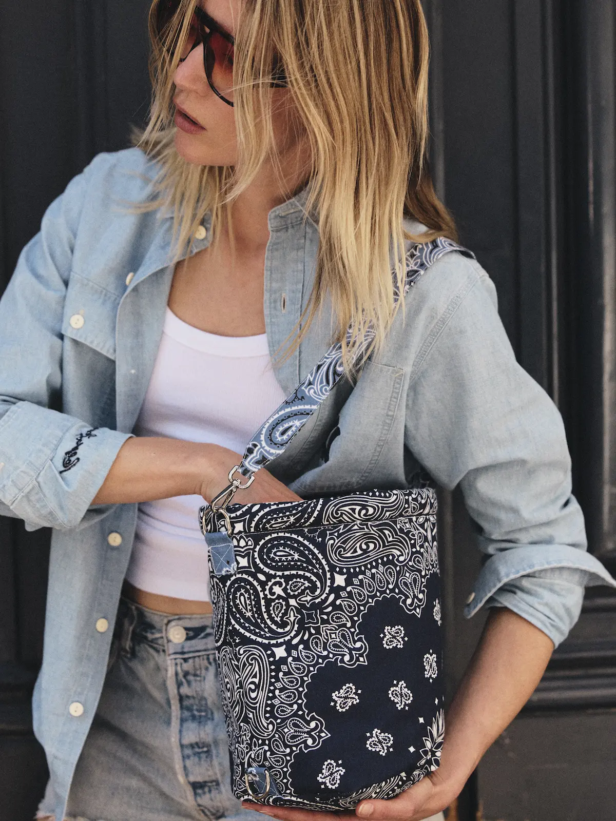 Navy bandana-print bucket bag worn crossbody with a wide patterned strap