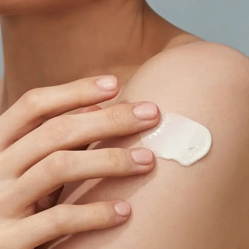 Sunscreen applied as white cream on shoulder, with hands spreading