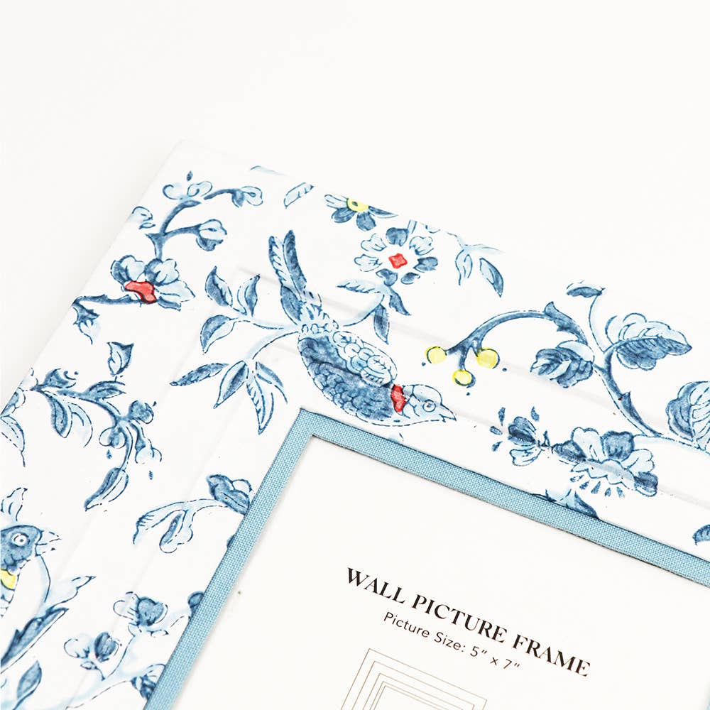 Wall picture frame close-up with blue floral print and captioned mat, slanted angle