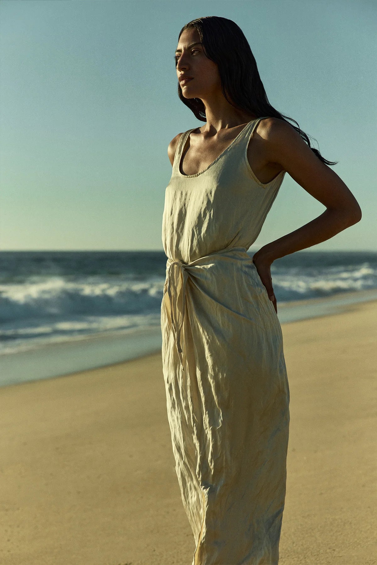 Cream sleeveless midi wrap dress on model, side view with tied waist and scoop neck
