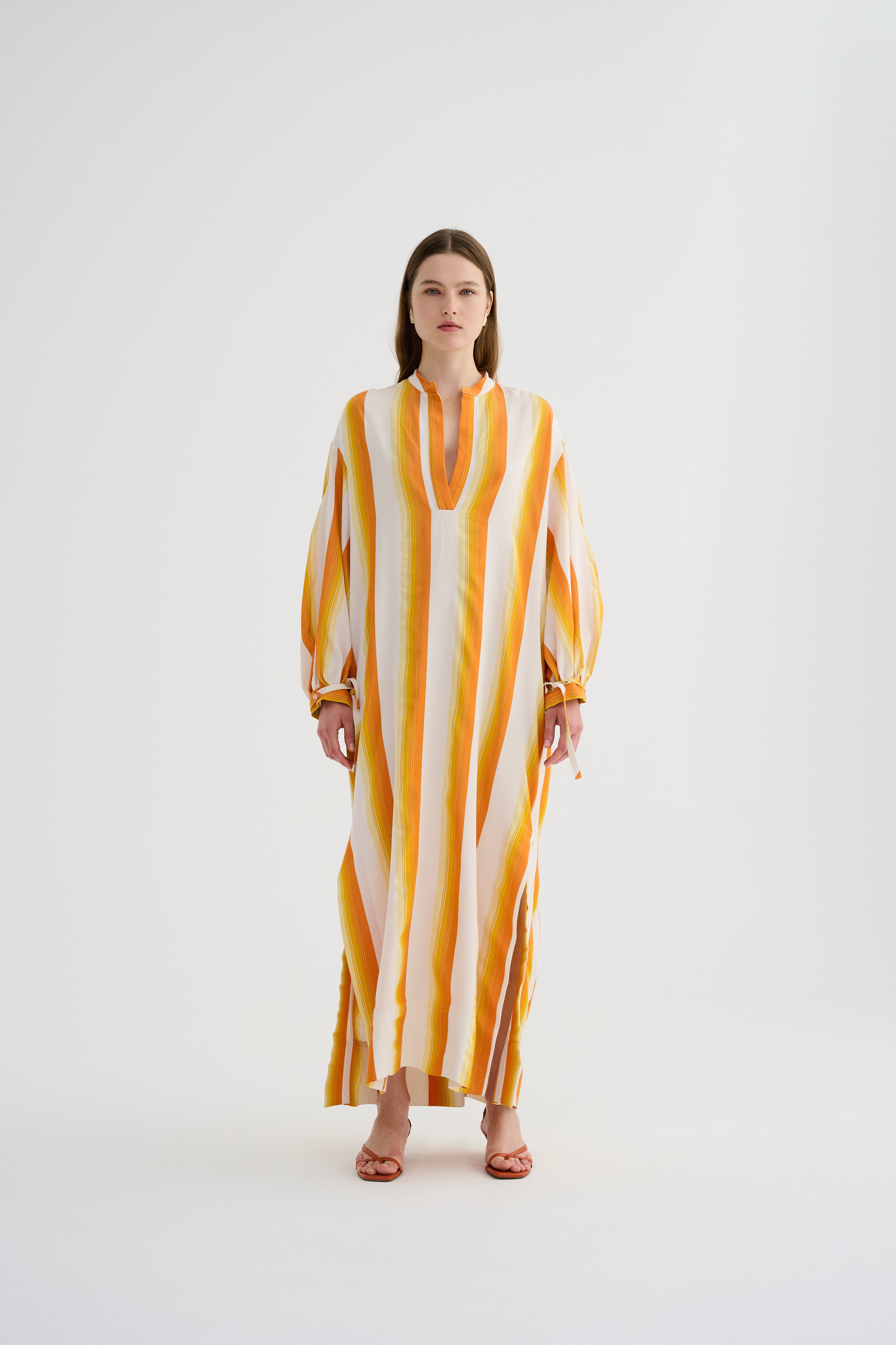Yellow maxi caftan dress with vertical orange-and-white stripes, V-neck, tied sleeve cuffs.
