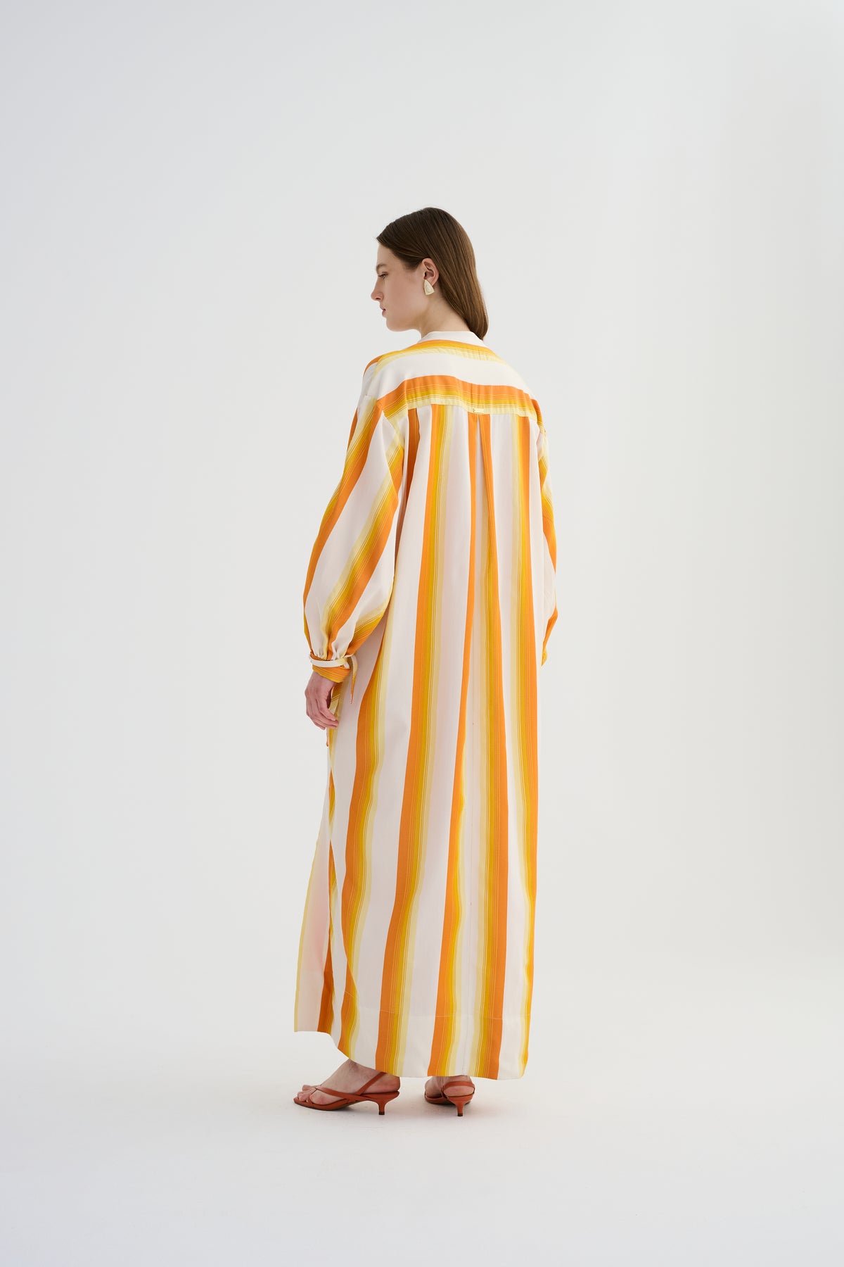 Yellow maxi caftan dress back view with vertical orange-and-white stripes and tied sleeve cuffs.
