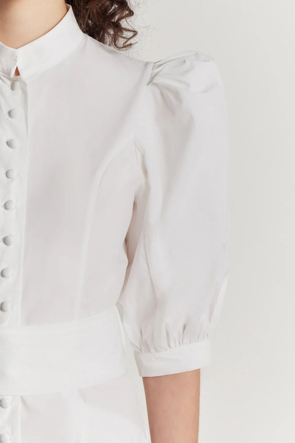 White short poplin dress close-up with puff sleeve, button placket and gathered cuff.