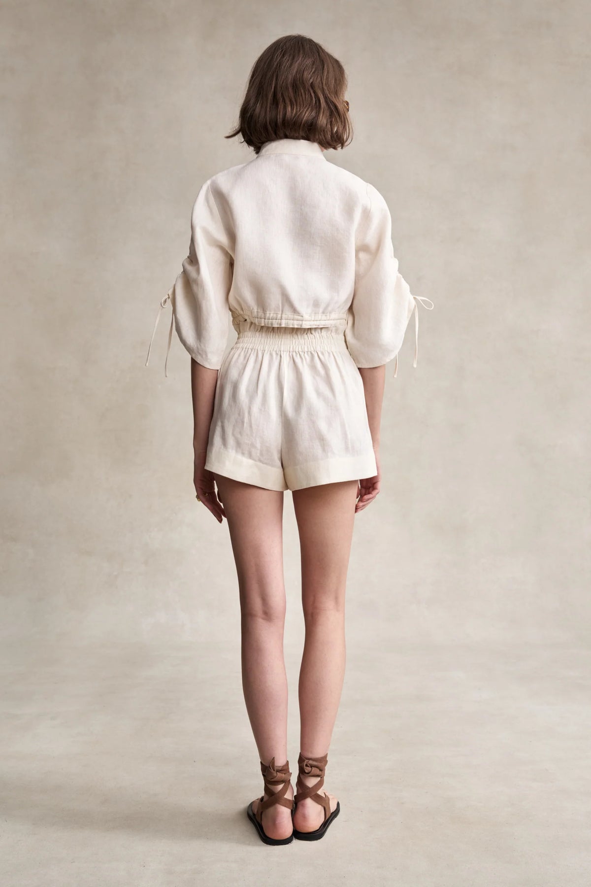 Off-white linen shorts back view with elastic waist and tied side bows