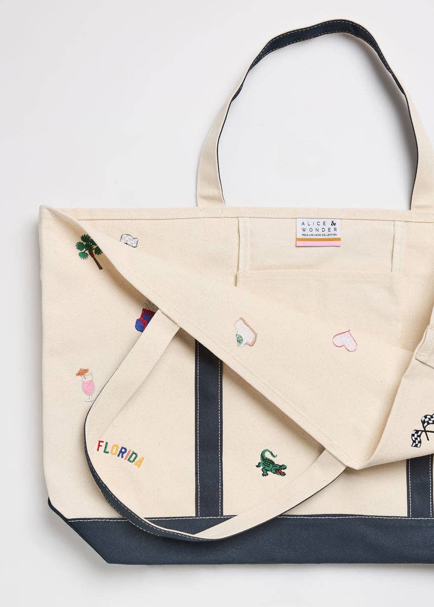 Canvas tote bag with navy side panels and handles, close-up of colorful Florida icons