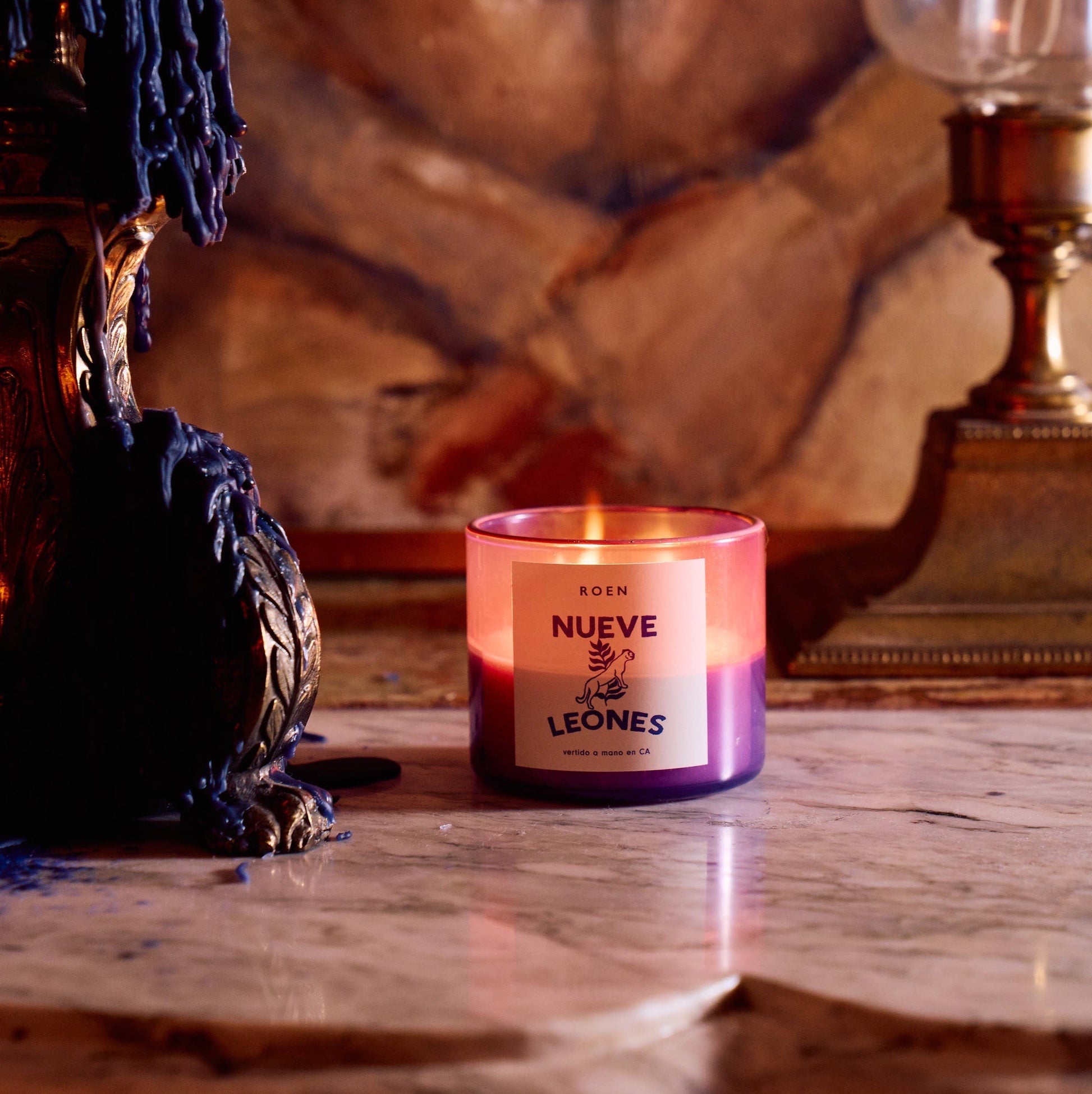 Scented candle in pink and purple glass jar with printed label