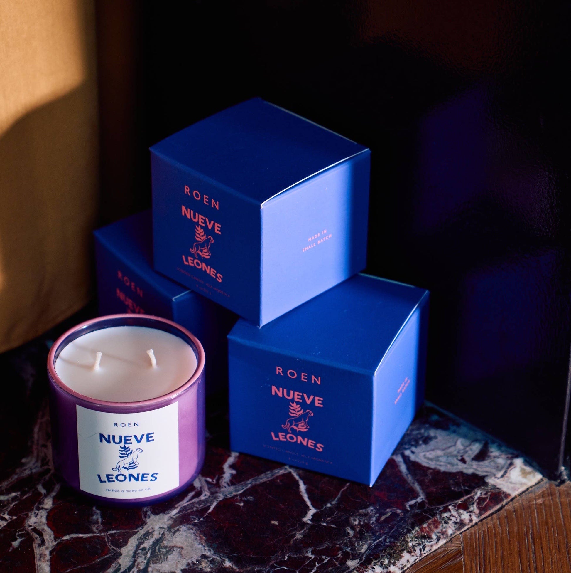 Pink scented candle in glass jar with white wax, plus two blue gift boxes
