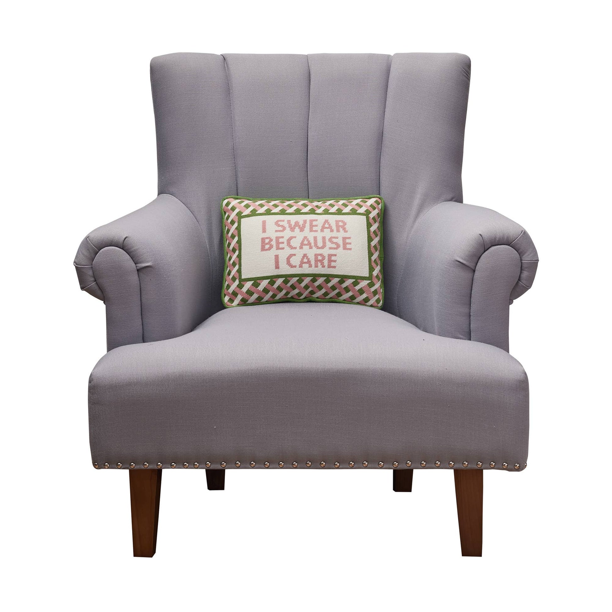 Embroidered throw pillow on armchair, 'I SWEAR BECAUSE I CARE' stitched on front