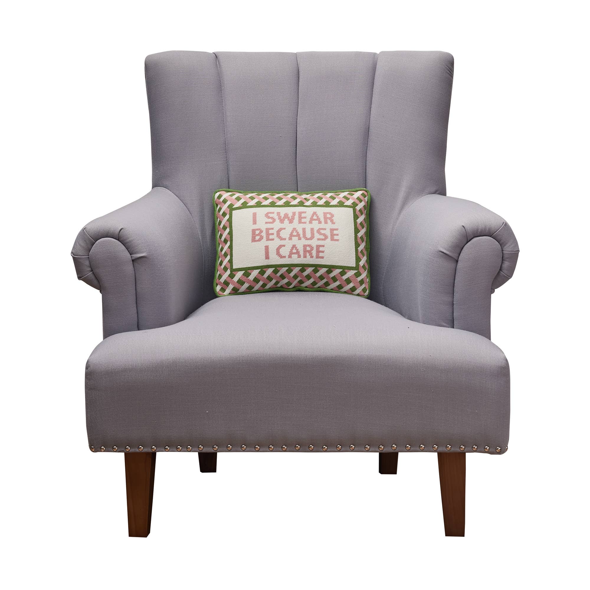 Embroidered throw pillow on armchair, 'I SWEAR BECAUSE I CARE' stitched on front