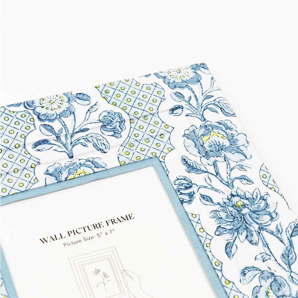 Wall picture frame corner close-up with blue floral and dotted trellis border, white insert