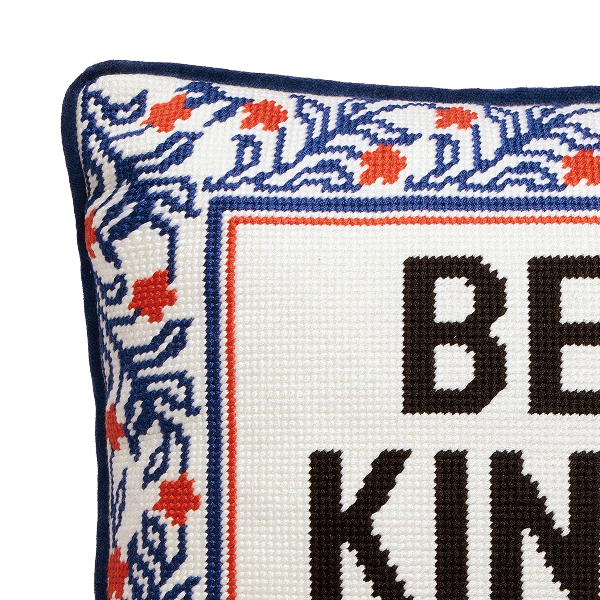 Embroidered pillow corner with navy border and "BE KIND" lettering on white