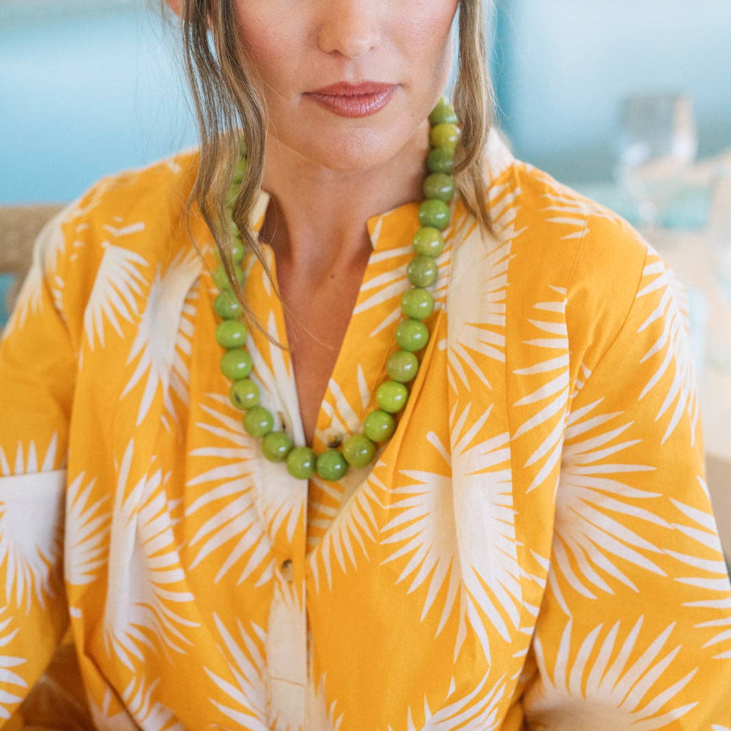 Green gumball bead necklace worn on a yellow patterned shirt