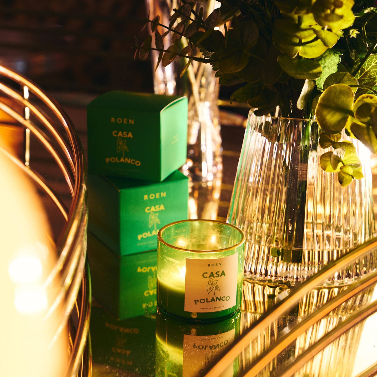 Green scented candle jar with CASA POLANCO label, green boxes behind