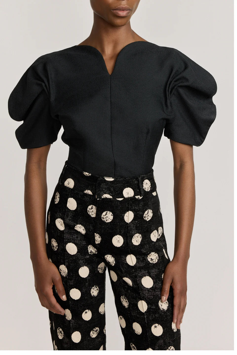 Black popelin top with V-neck and rounded short puff sleeves.