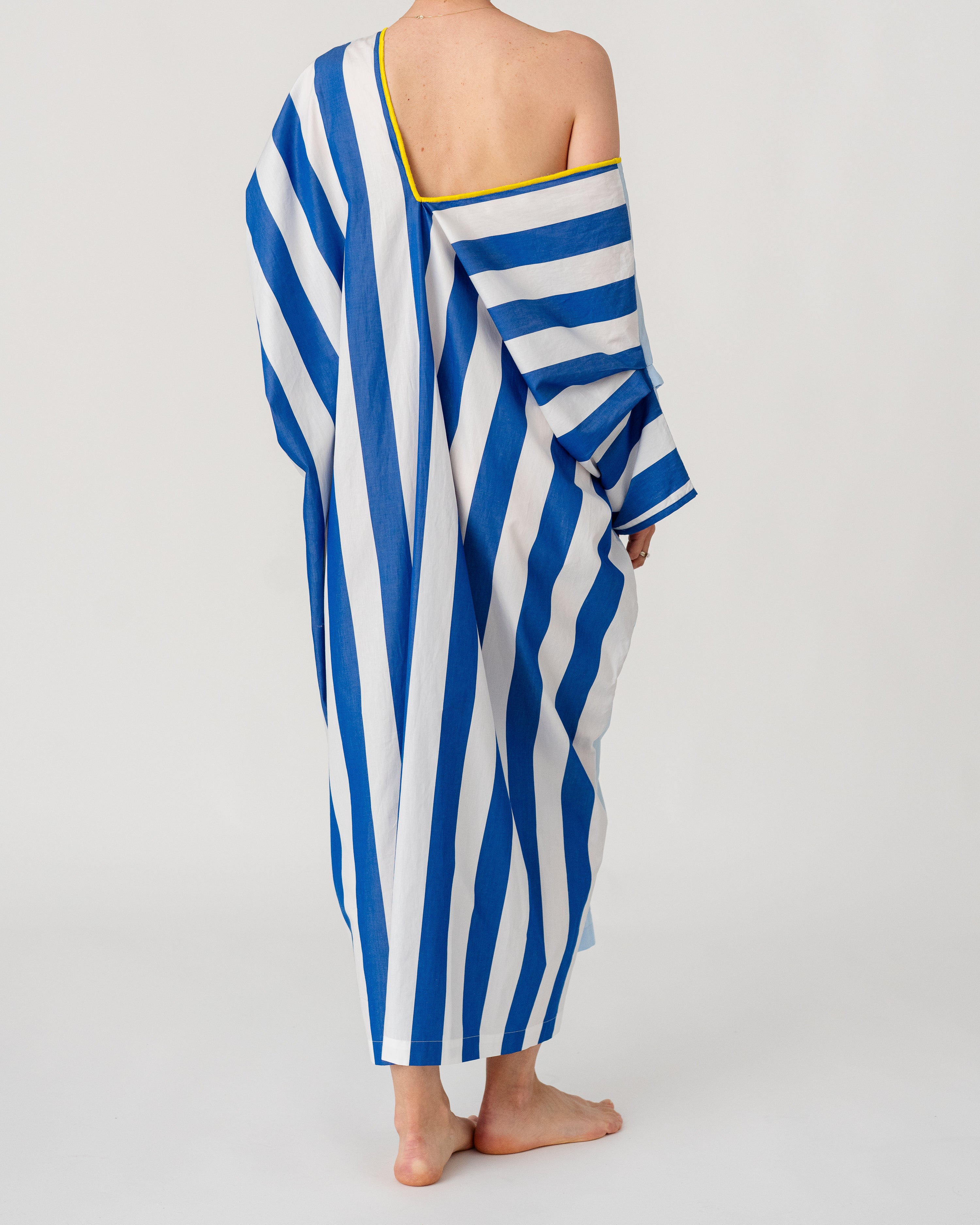 Draped caftan with one-shoulder look, blue-and-white stripes, V-neck and yellow trim.