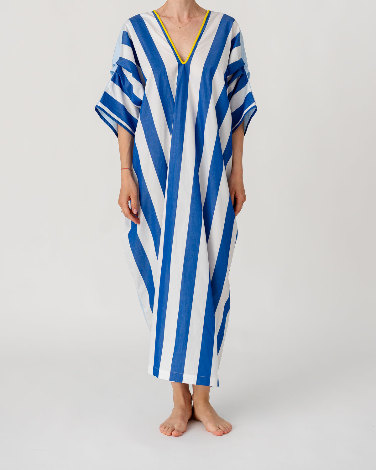 Loose caftan with batwing sleeves, blue-and-white vertical stripes and yellow-trim V-neck.