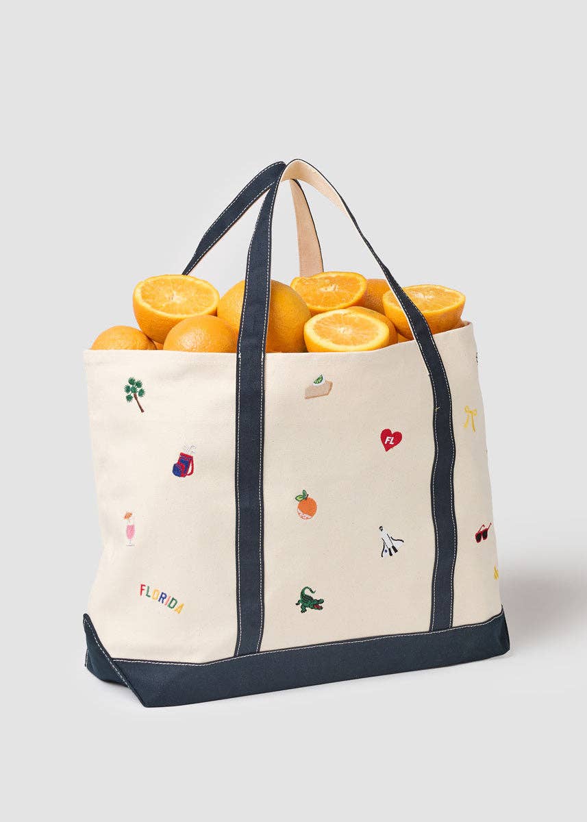 Canvas tote bag with navy handles and border, filled with oranges, Florida icons print