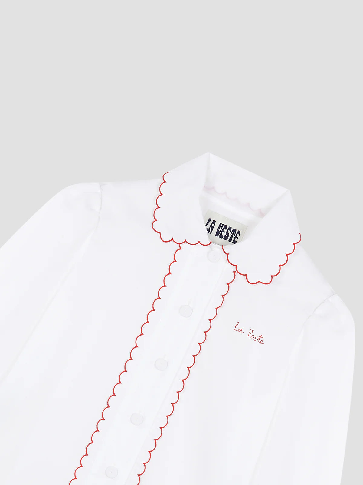 La Veste Blackboard shirt closeup: red scalloped collar and white buttons