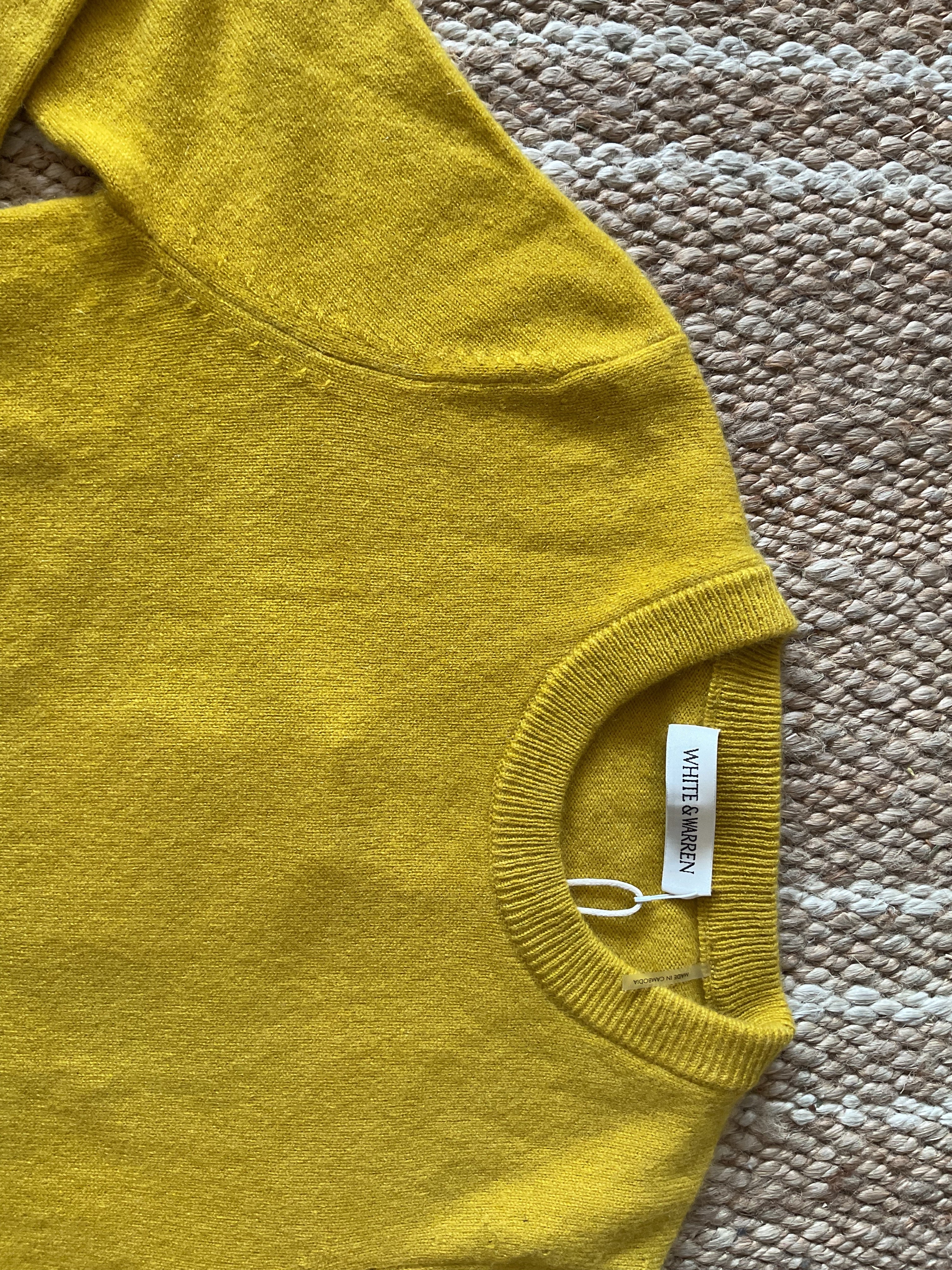 Mustard yellow knit crewneck sweater detail with ribbed neck and visible brand tag