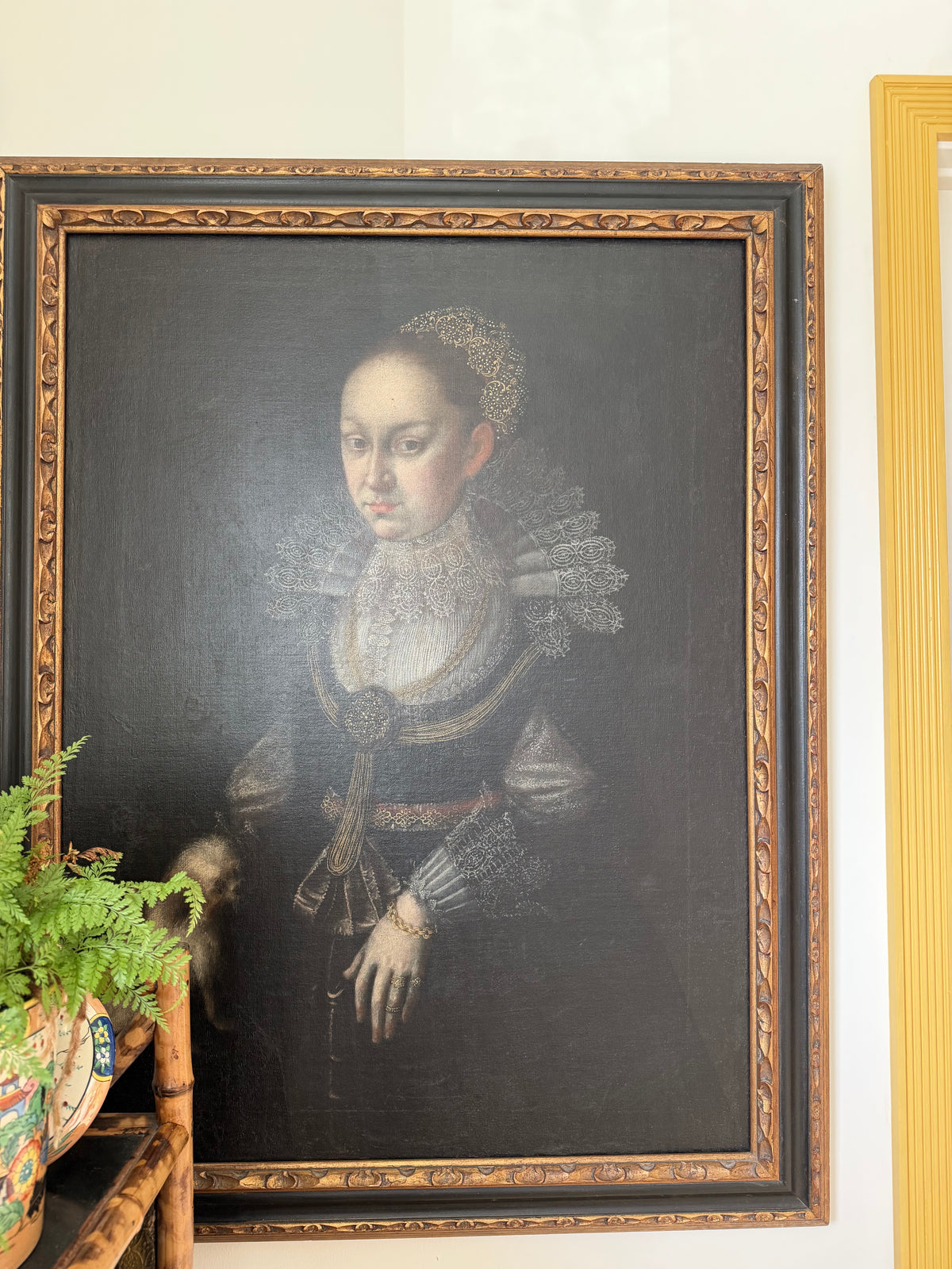 Framed portrait of a noblewoman holding prayer hands, wearing lace ruff and dark gown