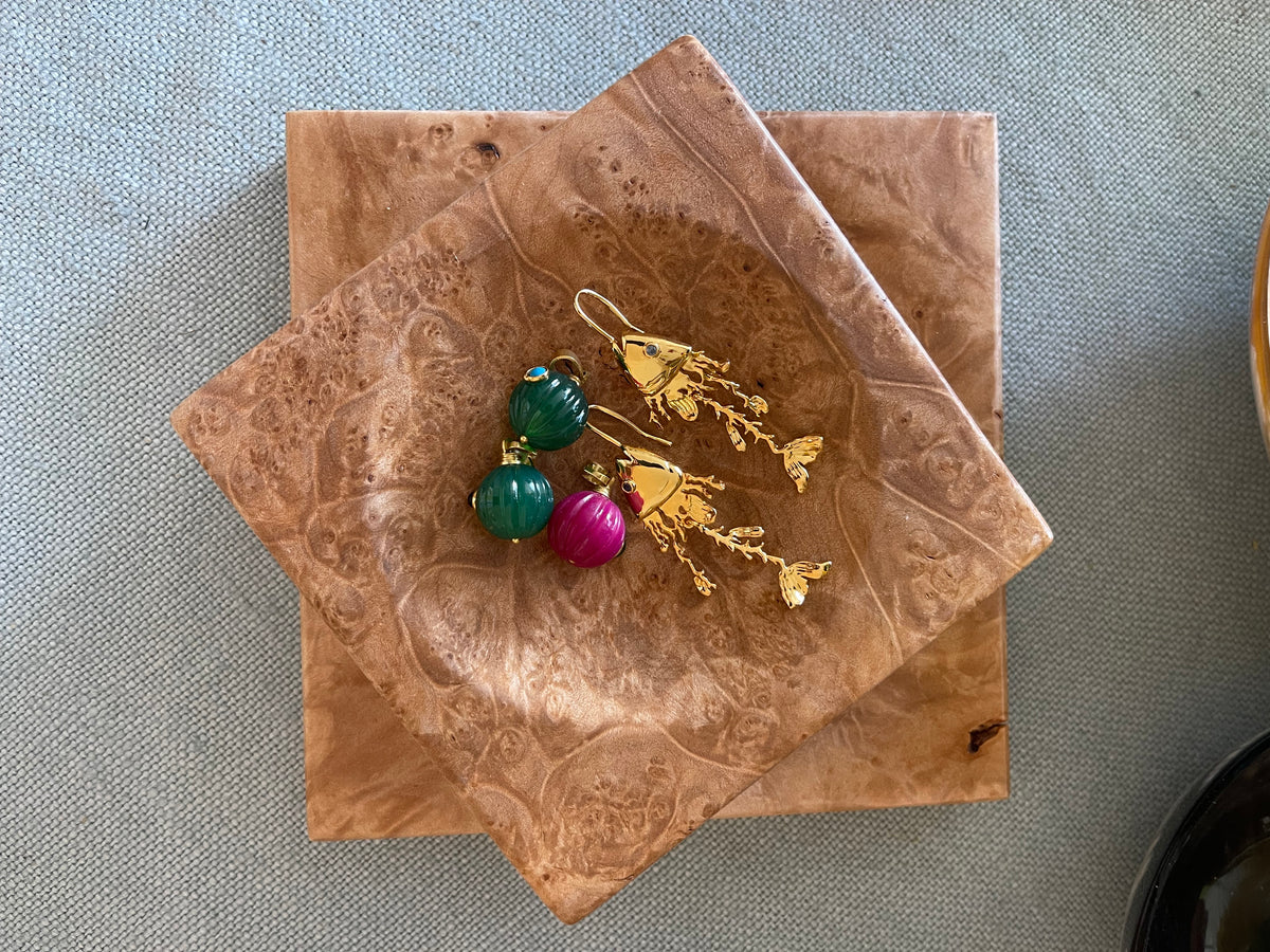 Two small burlwood dishes with warm brown grain and dangling bead earrings