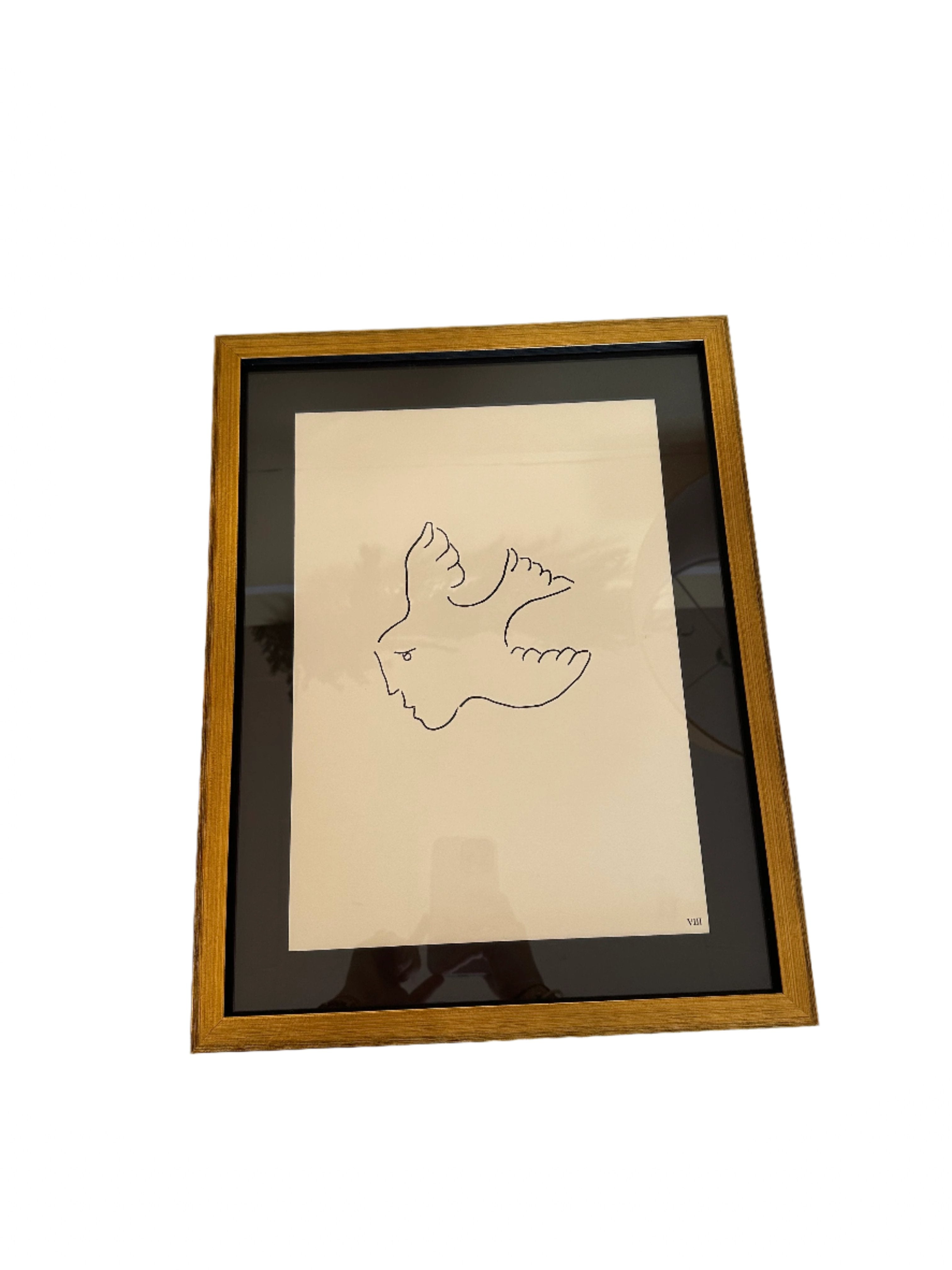 Framed line-art print with cream background and thin black drawing, in wood frame