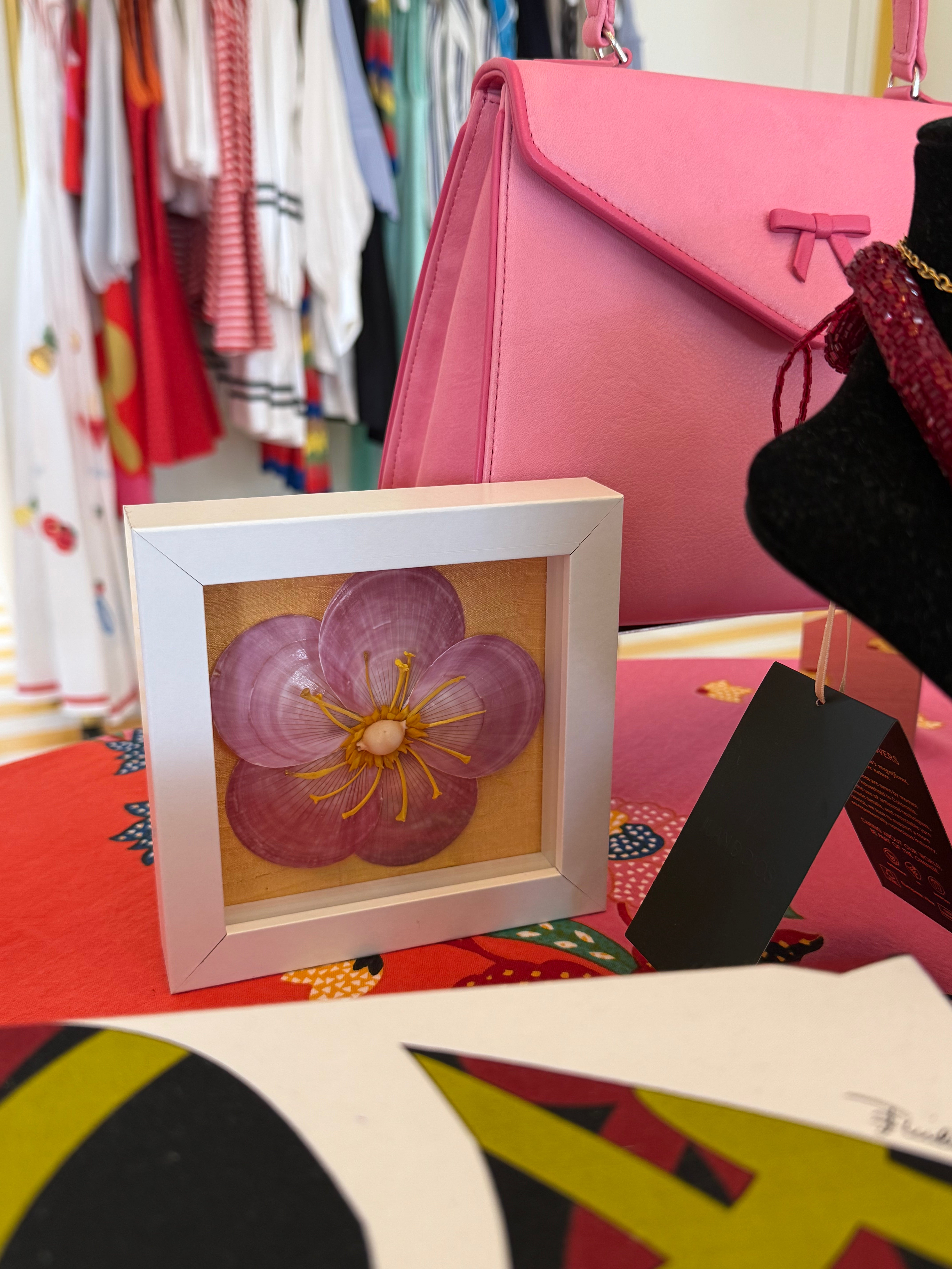 Small framed shell flower ornament with purple-pink petals and yellow center, white frame