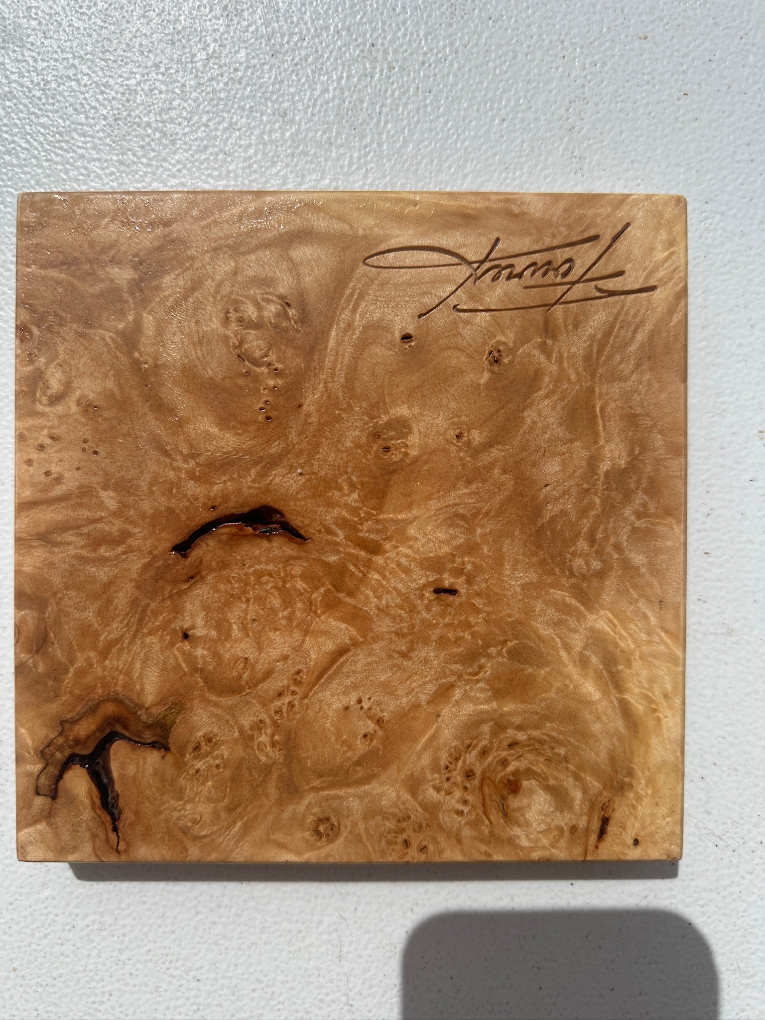 Small burlwood dish with warm brown grain and a handwritten signature on top