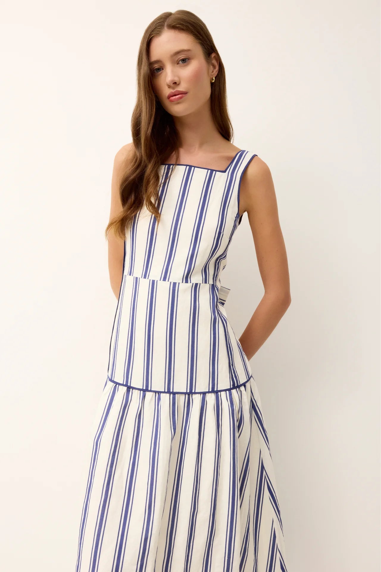 Sleeveless striped dress detail: square neckline, blue-and-white vertical stripes, tiered waist