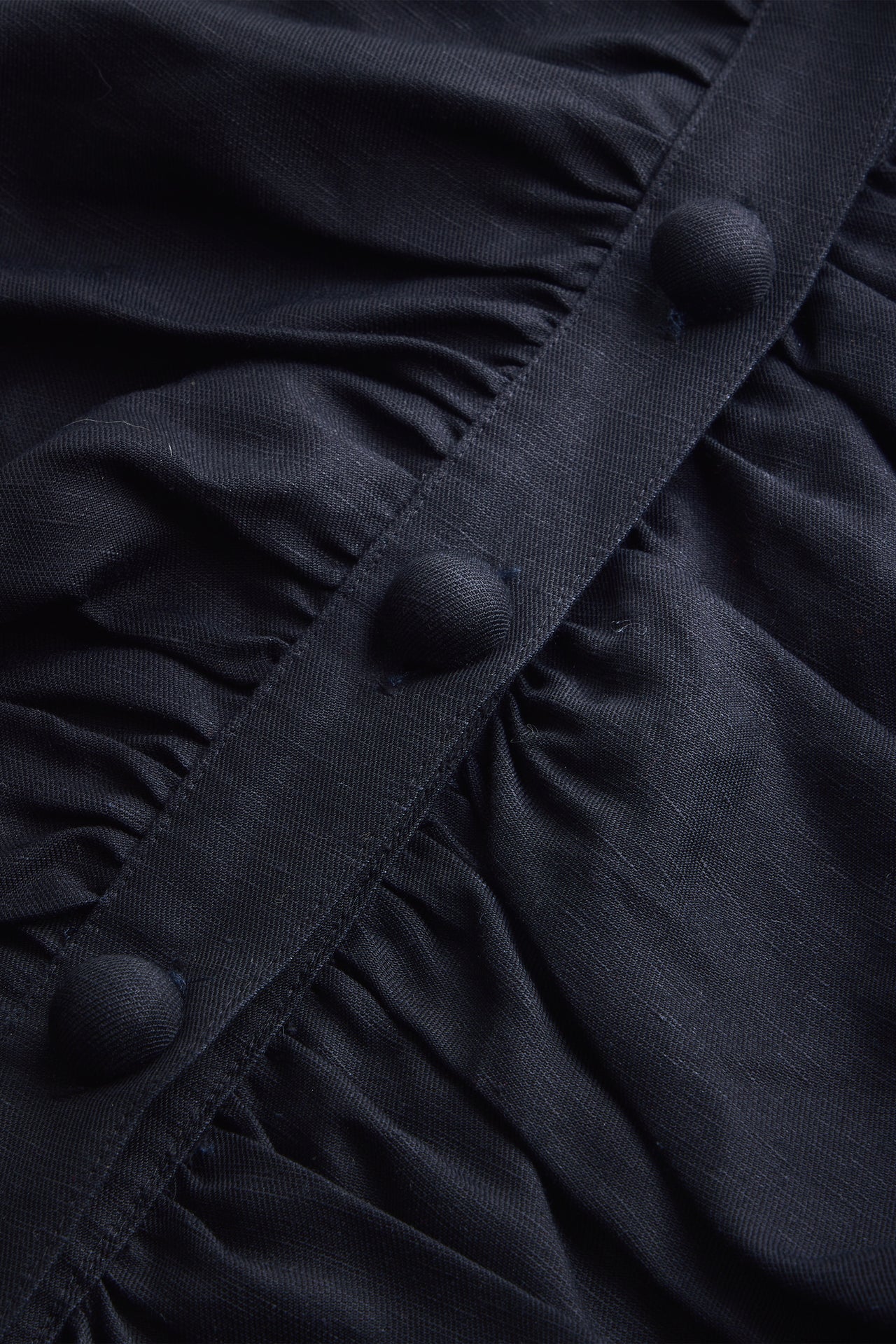 Close-up of black ruched top fabric with button placket detail