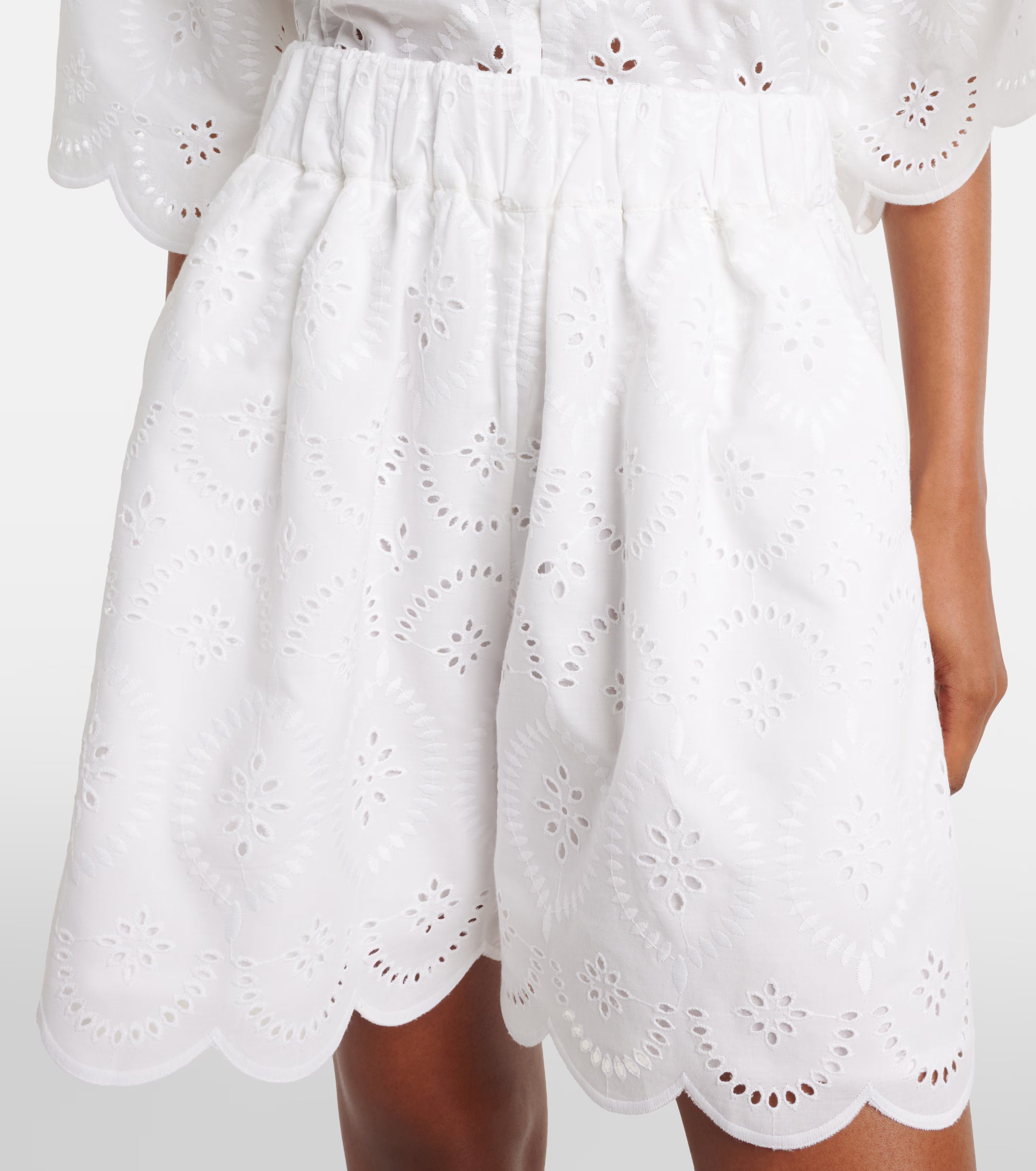 White eyelet shorts with elastic waistband, pleats, and scalloped hem