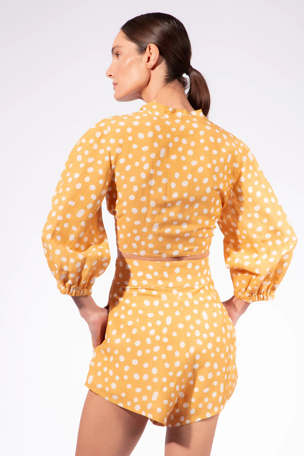 High-waisted polka dot shorts, back view, white dots on orange fabric