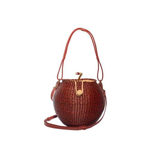 Woven coconut handbag with round basket shape, red top handles and adjustable shoulder strap
