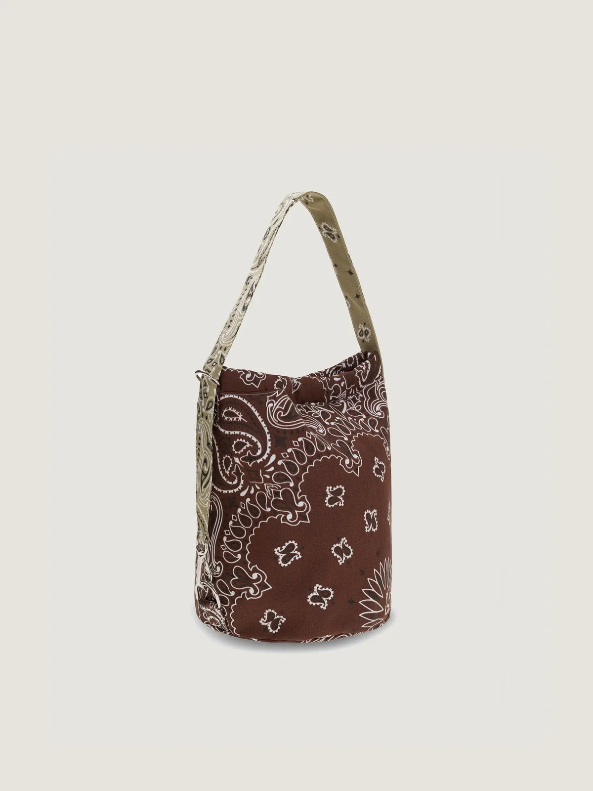 Side view of a brown bucket bag with a beige patterned strap and white bandana print