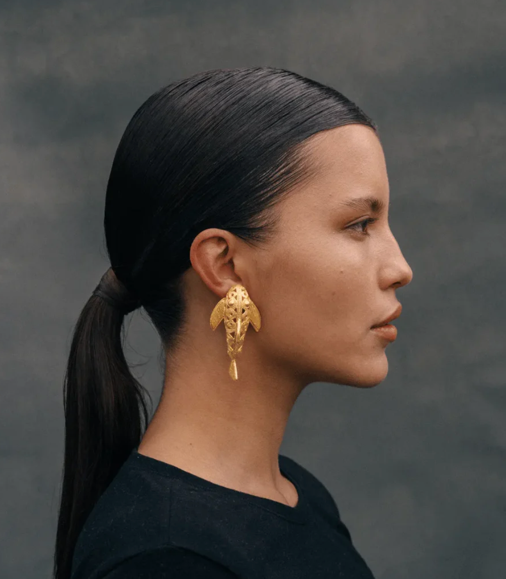 Gold filigree dangle earrings on model, triangular loop and long dangling drop.