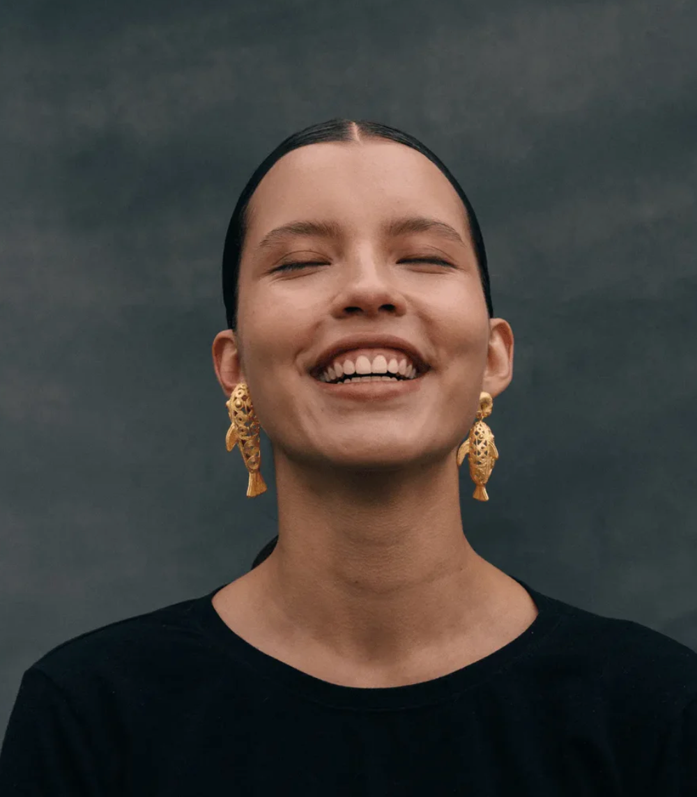Gold filigree dangle earrings on model, intricate teardrop motifs with long drops.
