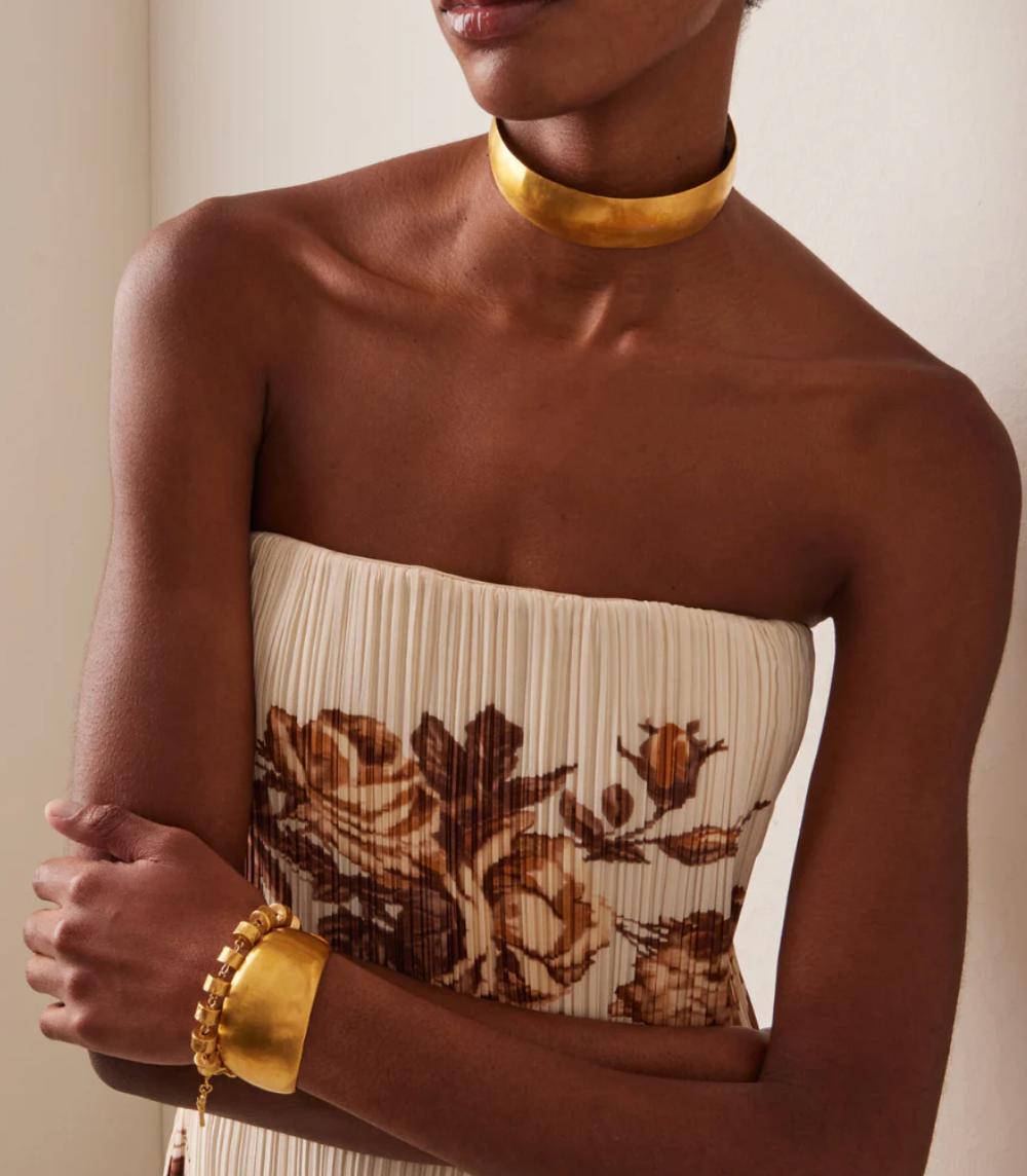 Gold choker worn at the base of the neck, smooth wide band