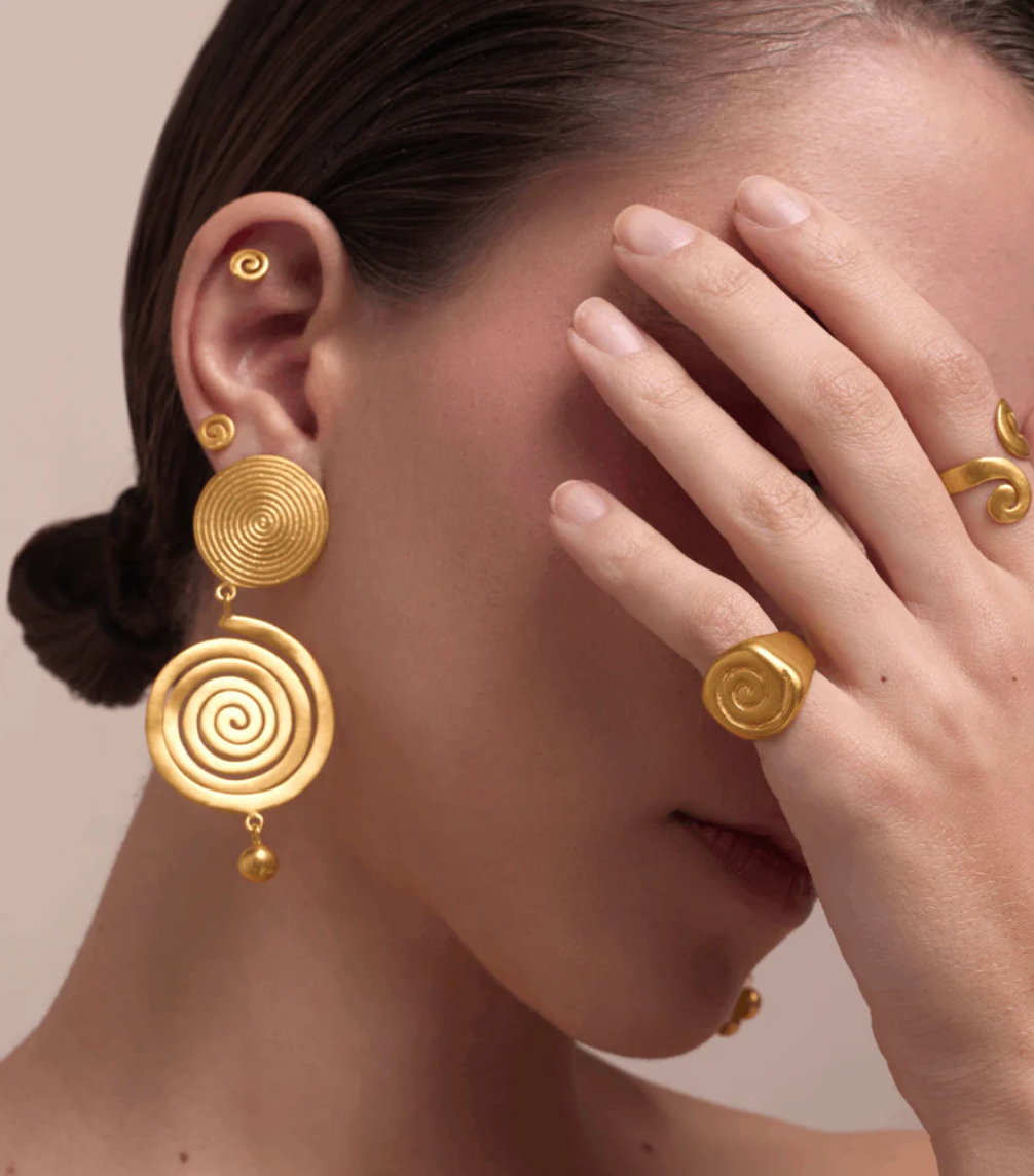 Gold spiral disc earrings with small bead drops, worn on ear