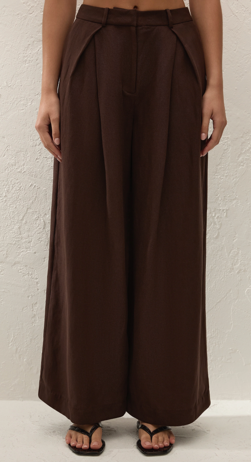 Chocolate high-rise wide-leg pants with pleated front and belt loops, model worn