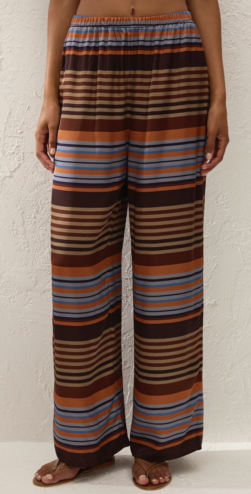 Striped wide-leg pants in brown with orange and blue horizontal stripes, front view