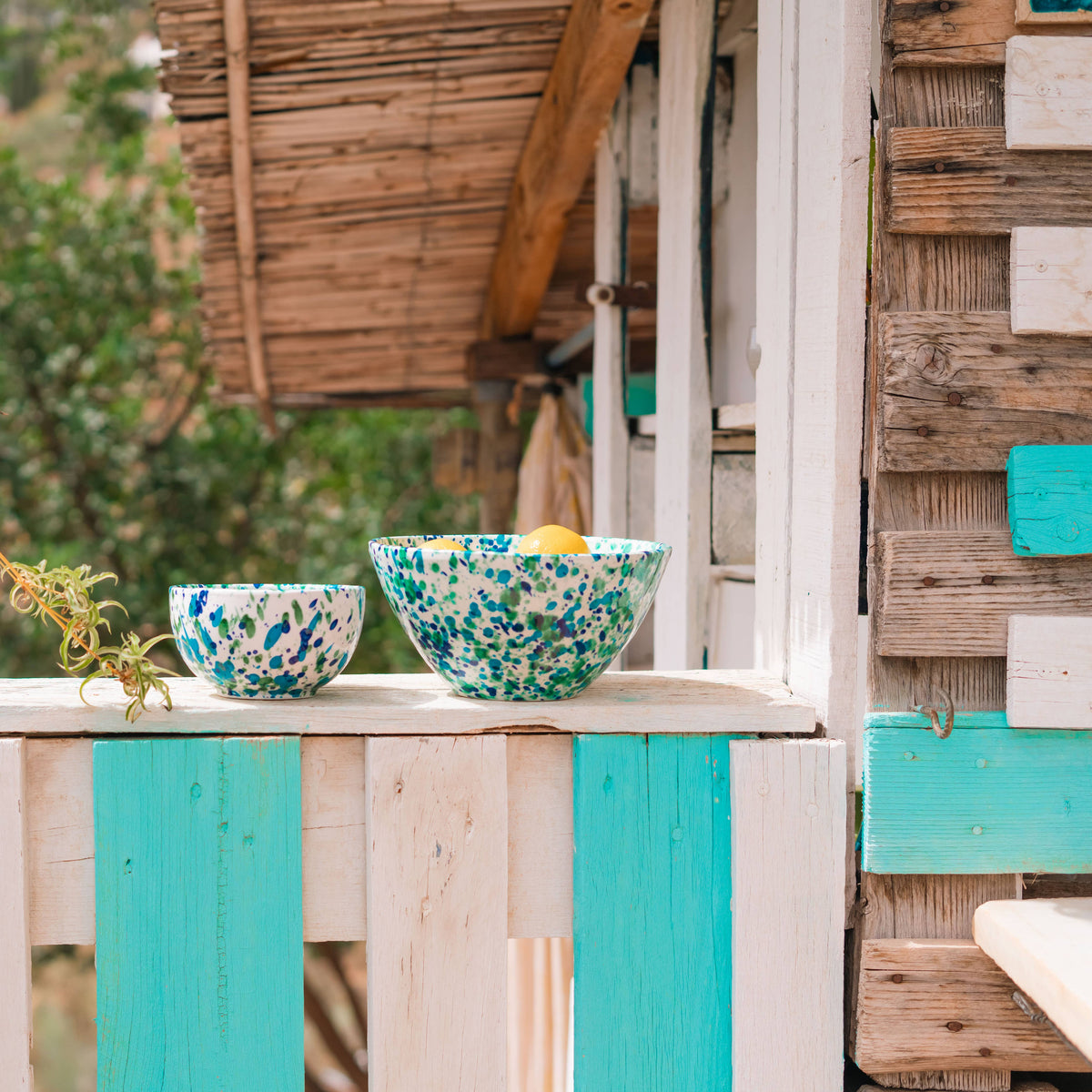 Large ceramic salad bowl with blue and green speckled finish on outdoor table