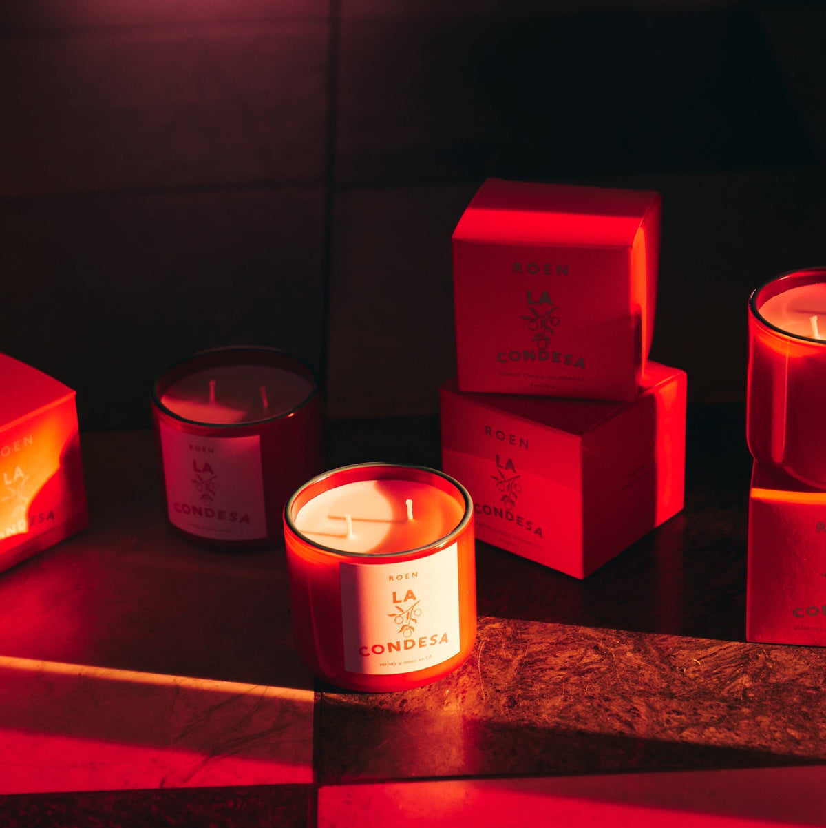 Scented candle in red glass with white label, with red gift boxes