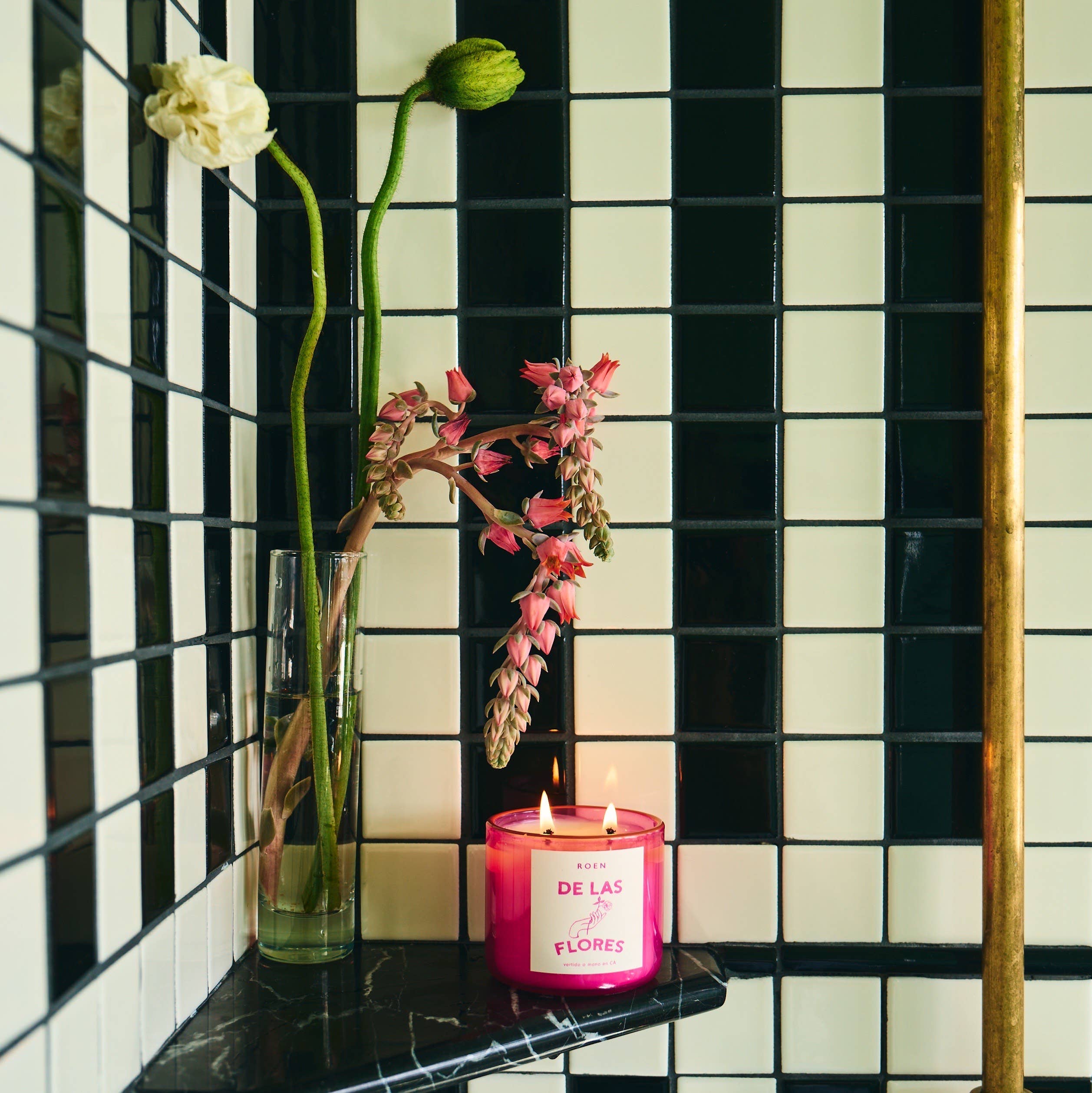Of the Flowers scented candle in a pink jar with lit wicks
