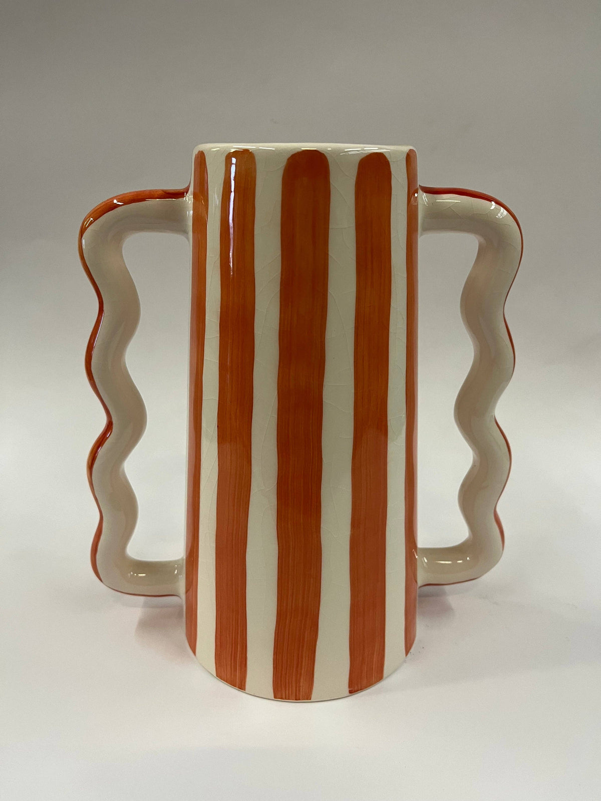 Small ceramic vase with wavy side handles and warm orange vertical stripes