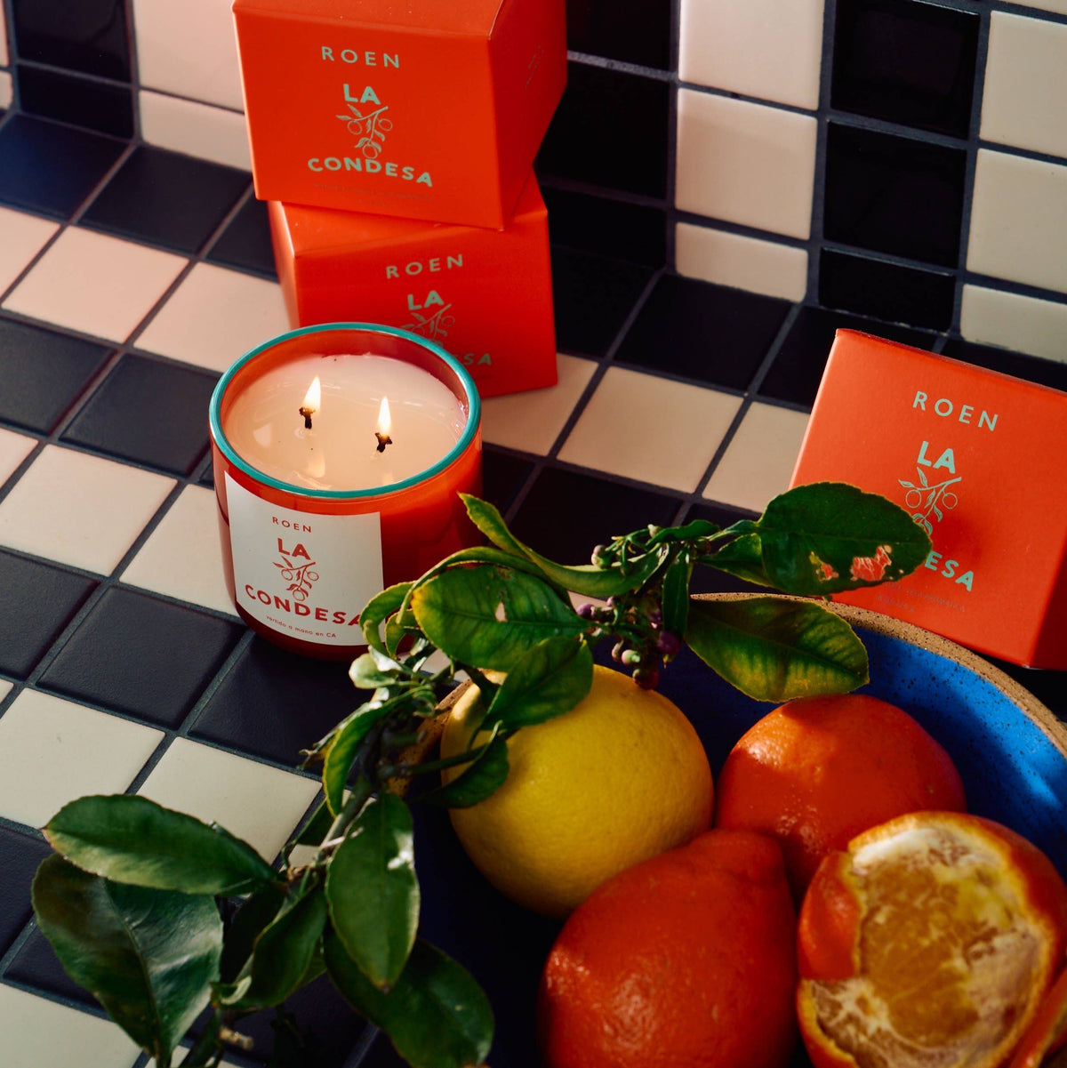 Scented candle in red glass with white label and red gift box on tile