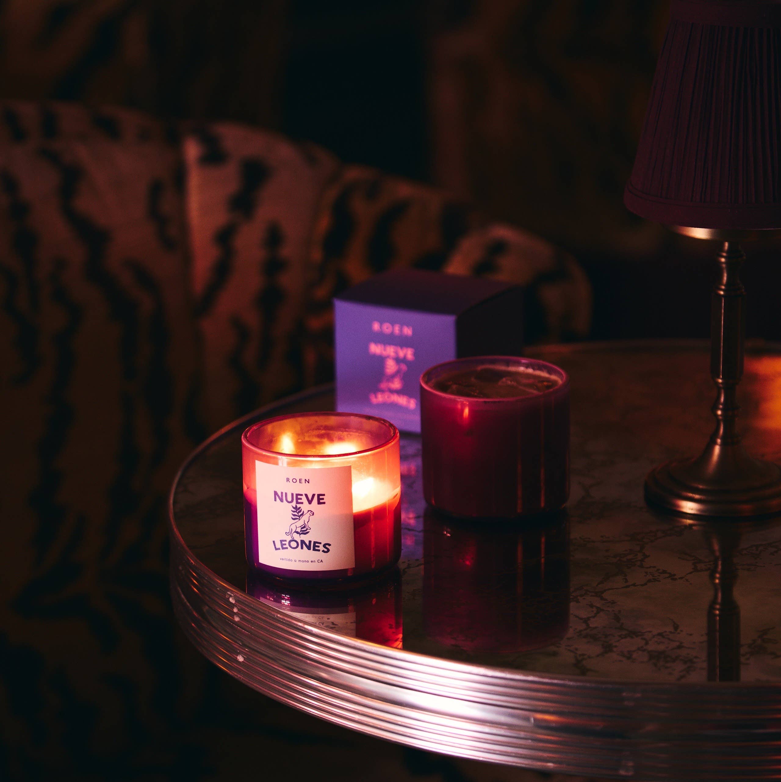 Two scented candles in red and pink glass jars on round tray