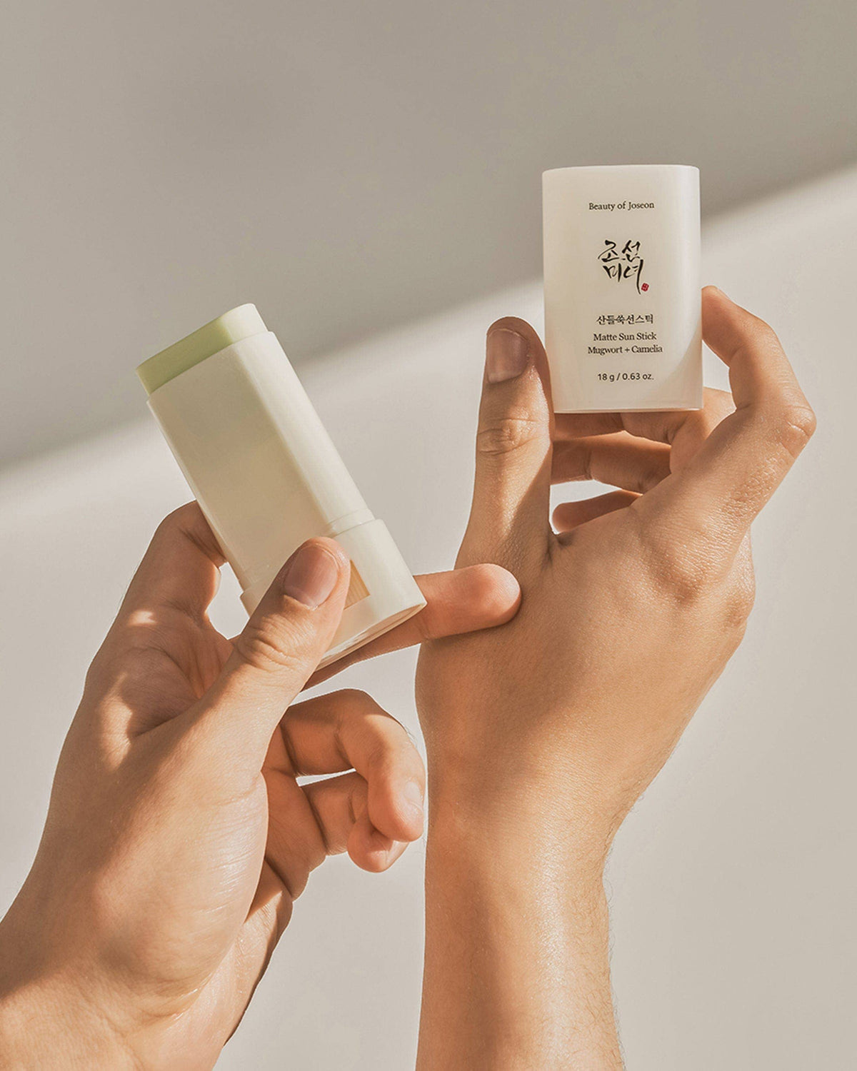 Beauty of Joseon Matt Sun Stick held in hands, white sunscreen stick with label