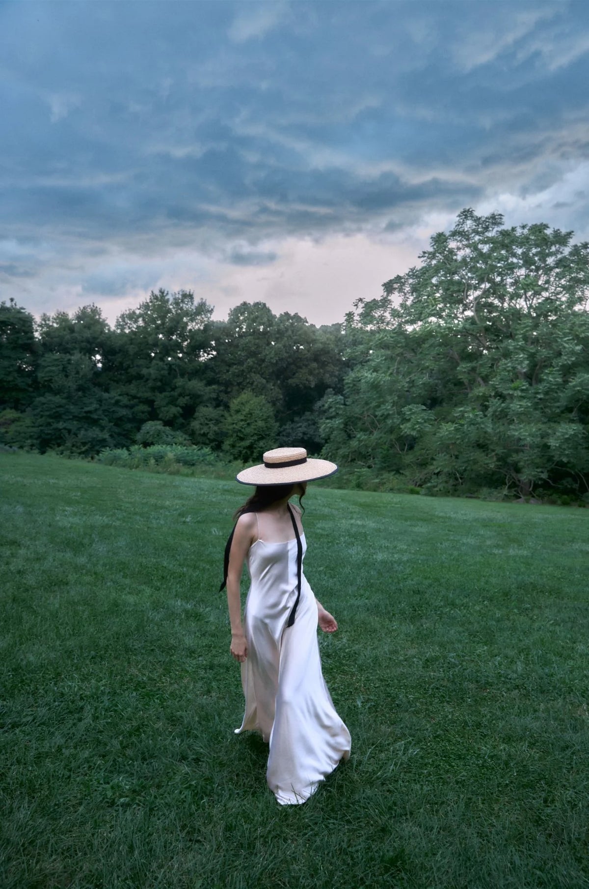 Person wearing Clairborne straw sun hat with black ribbon ties and wide brim